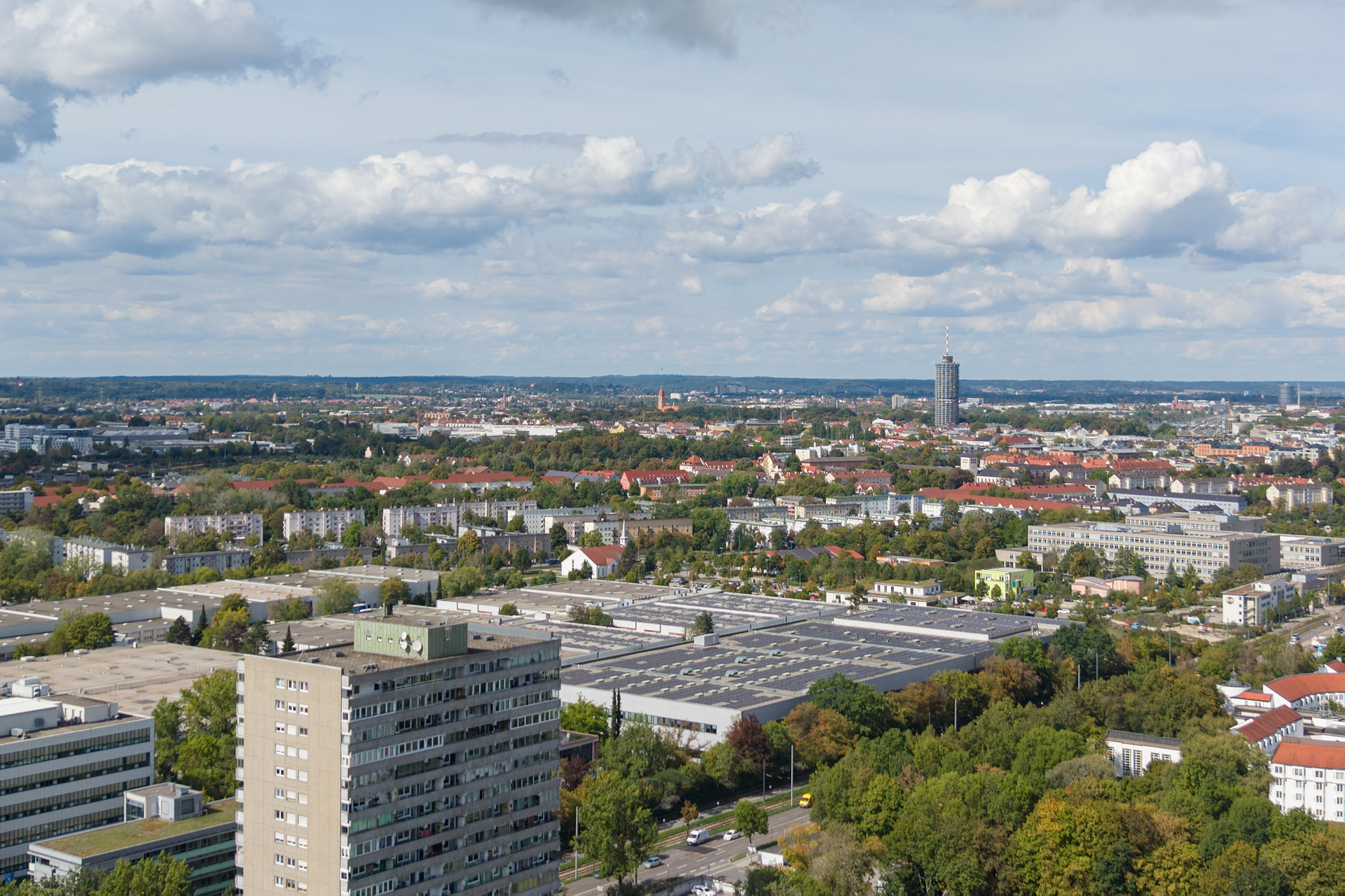 Drohnenaufnahme von Augsburg mit dem Hotelturm und begrünten Stadtquartieren.